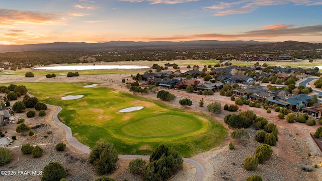 aerial view at dusk with view of golf course and a mountain view