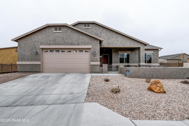 ranch-style house with concrete driveway, fence, an attached garage, and stucco siding