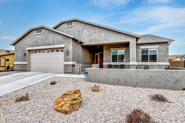 view of front facade with an attached garage, fence, concrete driveway, and stucco siding