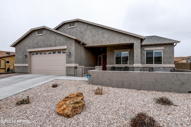 view of front of home featuring a garage, fence, driveway, and stucco siding