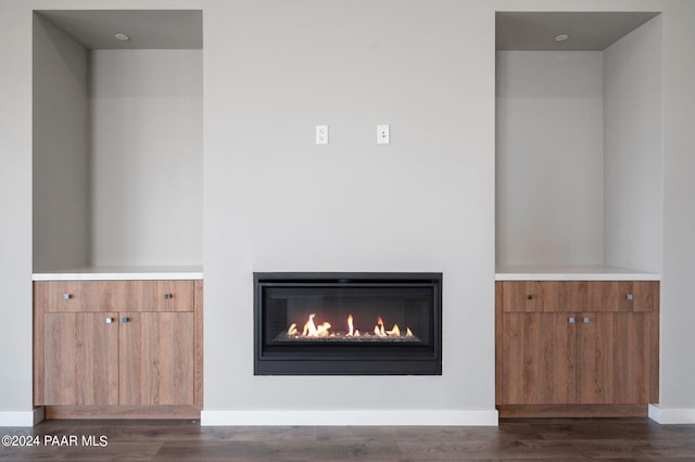 room details with a glass covered fireplace, baseboards, and wood finished floors