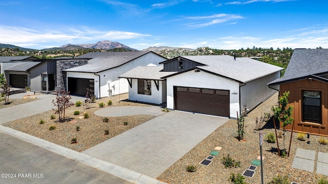 modern farmhouse featuring stucco siding, a mountain view, driveway, board and batten siding, and an attached garage