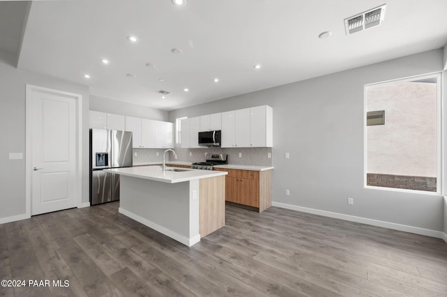 kitchen with visible vents, wood finished floors, a sink, stainless steel appliances, and decorative backsplash