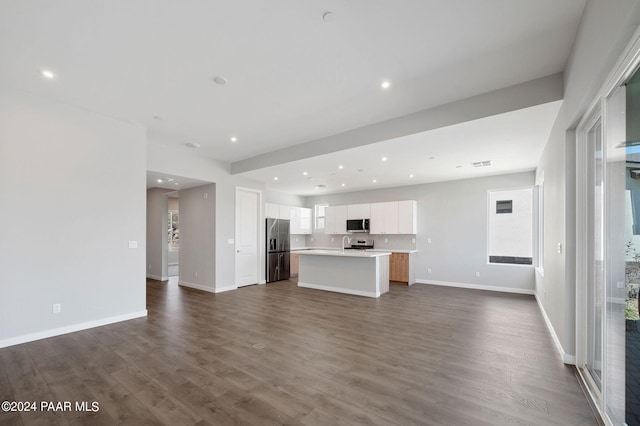 kitchen with appliances with stainless steel finishes, a kitchen island with sink, dark wood-style flooring, light countertops, and open floor plan