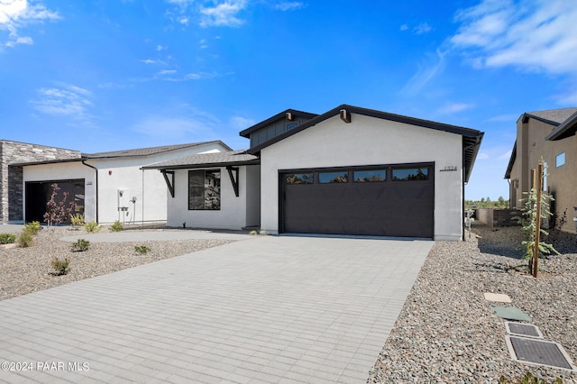 view of front of house featuring an attached garage, stucco siding, and decorative driveway