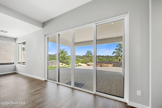 entryway with wood finished floors, baseboards, and visible vents