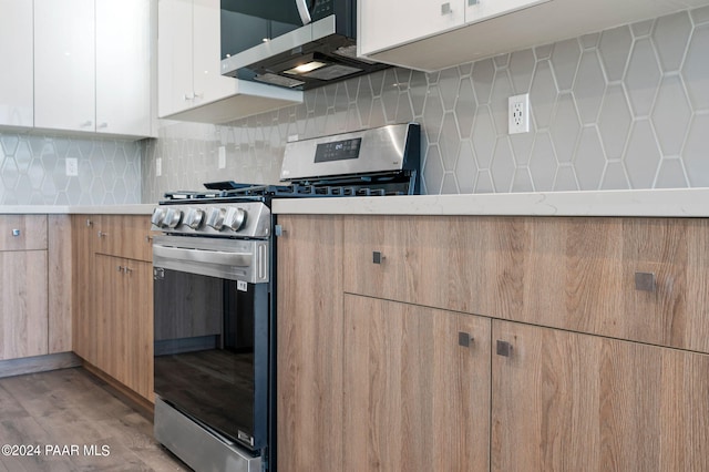 kitchen with light wood-type flooring, light countertops, backsplash, white cabinets, and stainless steel appliances