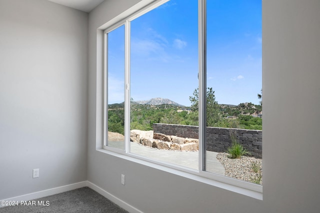 unfurnished room with carpet flooring, baseboards, and a mountain view