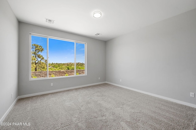 carpeted spare room featuring visible vents and baseboards