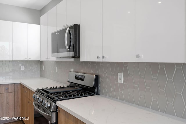 kitchen featuring white cabinets, light stone countertops, tasteful backsplash, and stainless steel appliances