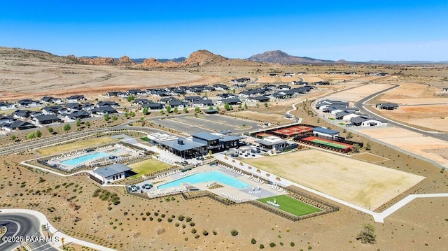 aerial perspective of suburban area with a pool area, a mountain backdrop, and a desert landscape