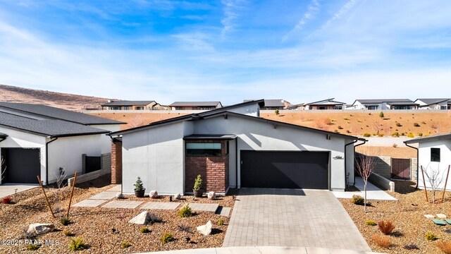 view of front of property with a garage, a residential view, decorative driveway, and stucco siding