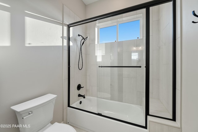 bathroom featuring enclosed tub / shower combo and toilet