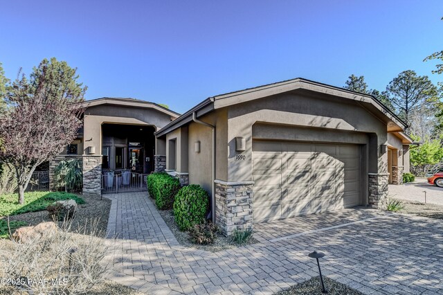 1690 Stable Rock Rd, Prescott, AZ 86303 - view of front of house featuring stucco siding, decorative driveway, an attached garage, and stone siding