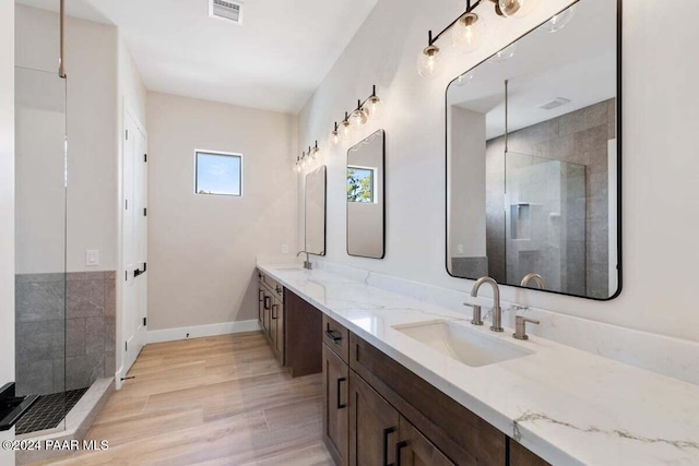 bathroom with hardwood / wood-style floors, vanity, and tiled shower