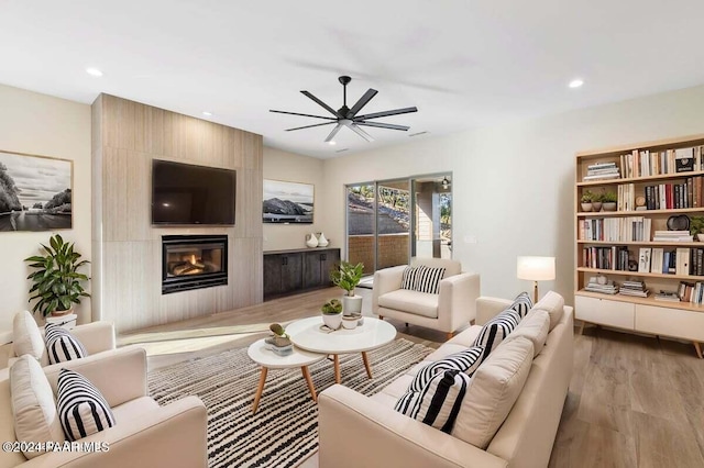 living room with a fireplace, light hardwood / wood-style flooring, and ceiling fan