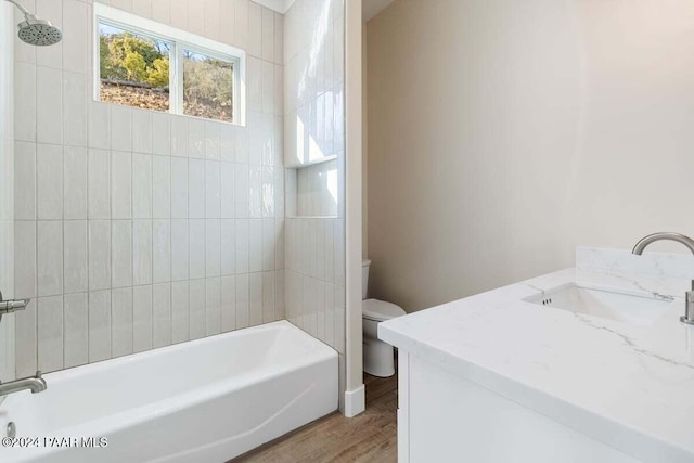 full bathroom with vanity, wood-type flooring, tiled shower / bath combo, and toilet