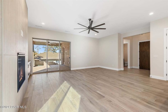 unfurnished living room featuring ceiling fan and light wood-type flooring