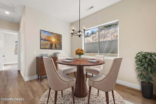 dining space with light wood-type flooring and an inviting chandelier