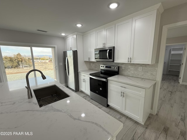 kitchen featuring white cabinets, light stone countertops, sink, and appliances with stainless steel finishes