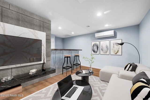 living room featuring a wall mounted air conditioner and light wood-type flooring