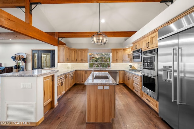 kitchen with kitchen peninsula, appliances with stainless steel finishes, decorative light fixtures, a kitchen island, and decorative backsplash