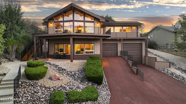 back house at dusk with a balcony and a garage