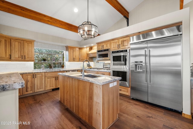 kitchen featuring pendant lighting, appliances with stainless steel finishes, tasteful backsplash, sink, and a kitchen island with sink