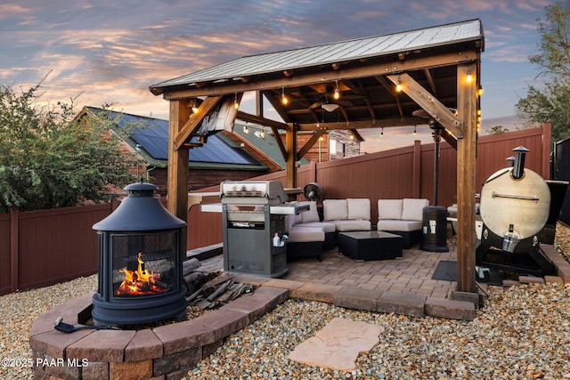 patio terrace at dusk featuring a gazebo, grilling area, outdoor lounge area, and ceiling fan