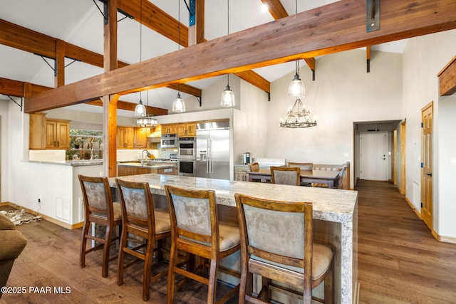 kitchen with hardwood / wood-style floors, stainless steel appliances, decorative backsplash, hanging light fixtures, and a chandelier