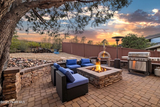 patio terrace at dusk with area for grilling and an outdoor fire pit