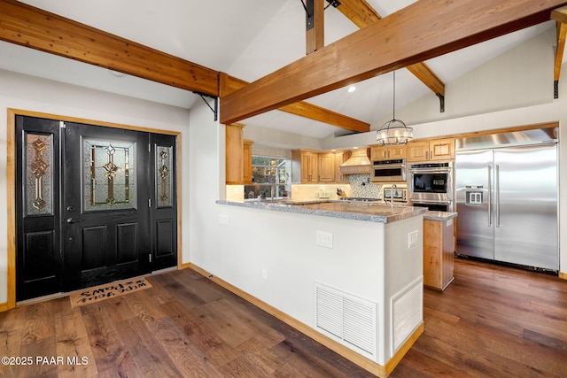 kitchen with hanging light fixtures, kitchen peninsula, backsplash, stainless steel appliances, and lofted ceiling with beams