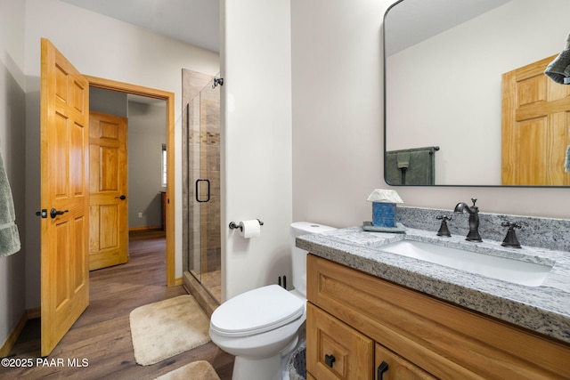 bathroom with vanity, hardwood / wood-style floors, a shower with shower door, and toilet