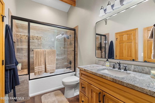 full bathroom featuring hardwood / wood-style flooring, bath / shower combo with glass door, vanity, and toilet