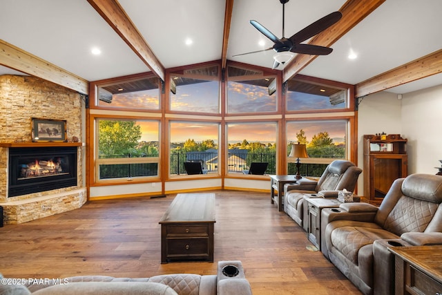 living room featuring lofted ceiling with beams, wood-type flooring, ceiling fan, and a fireplace