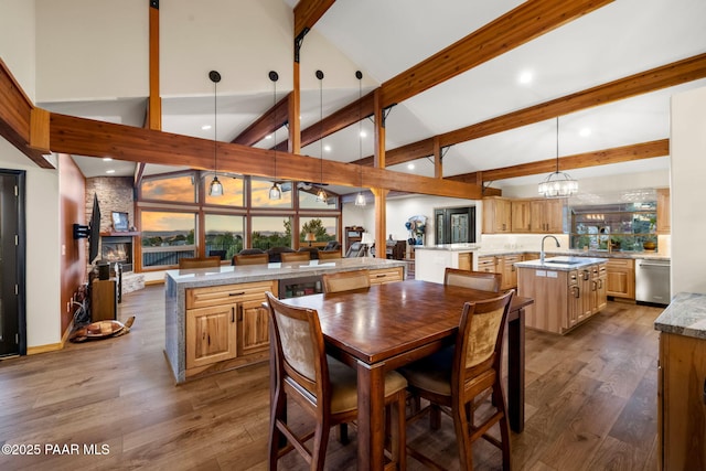 dining space featuring beamed ceiling, wood-type flooring, a fireplace, and sink