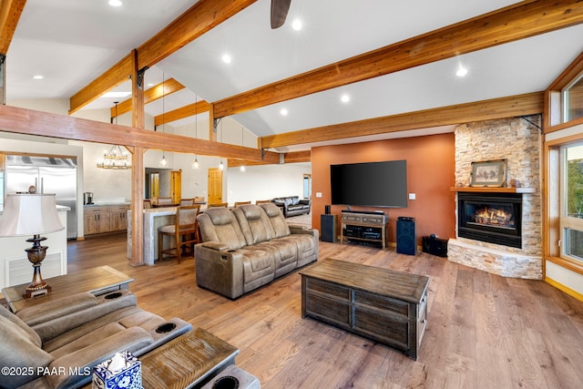 living room featuring lofted ceiling with beams, a fireplace, and light hardwood / wood-style floors