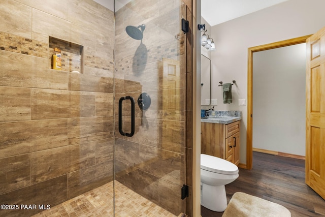 bathroom featuring hardwood / wood-style flooring, vanity, a shower with door, and toilet