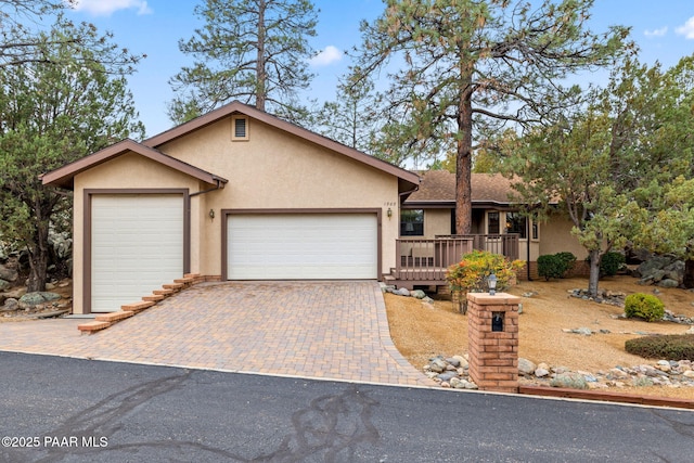 ranch-style house featuring decorative driveway, an attached garage, and stucco siding