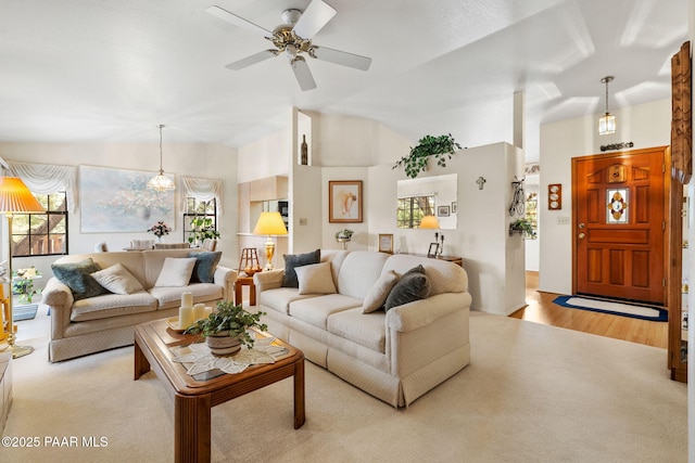 carpeted living area featuring lofted ceiling, wood finished floors, and ceiling fan