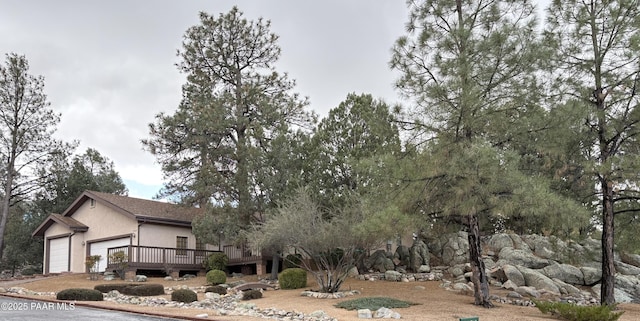 view of home's exterior featuring stucco siding, a deck, and an attached garage