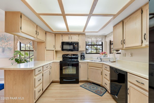 kitchen with light wood finished floors, light brown cabinetry, a peninsula, black appliances, and a sink