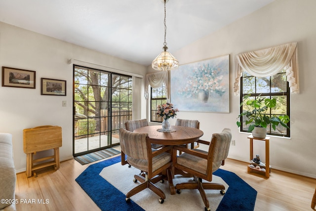 dining space featuring vaulted ceiling, a notable chandelier, baseboards, and light wood finished floors