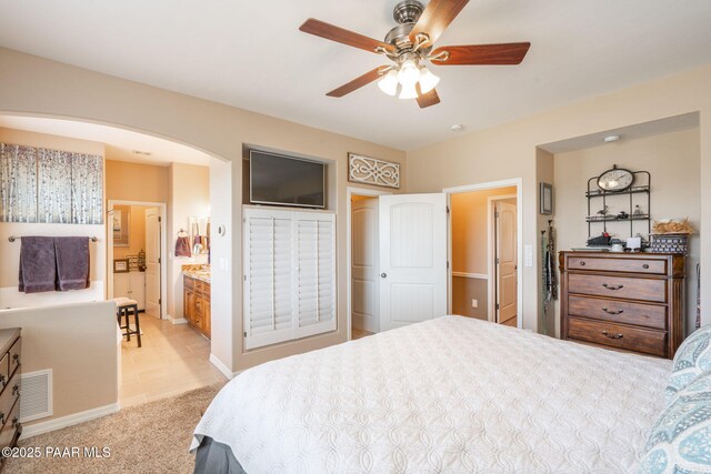 4995 Cactus Pl, Prescott, AZ 86301 - bedroom featuring arched walkways, light carpet, baseboards, connected bathroom, and ceiling fan