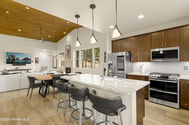 kitchen with pendant lighting, high vaulted ceiling, ceiling fan, appliances with stainless steel finishes, and light hardwood / wood-style floors