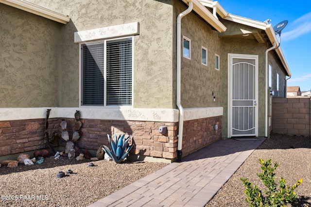 entrance to property with fence and stucco siding