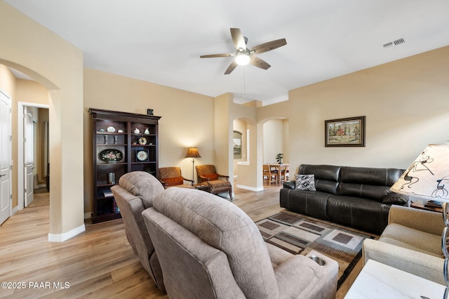 living room featuring arched walkways, baseboards, visible vents, and light wood-style floors