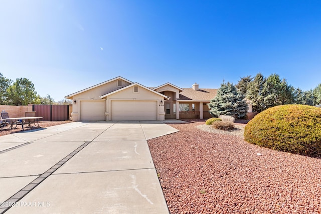 single story home with a garage, stucco siding, driveway, and fence