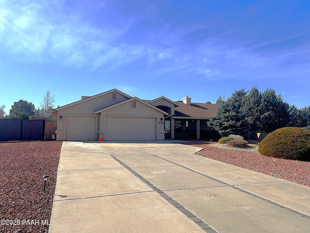 single story home with stucco siding, driveway, an attached garage, and fence