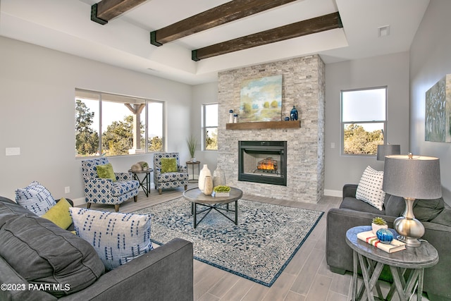 living room featuring beam ceiling, a stone fireplace, and light hardwood / wood-style floors